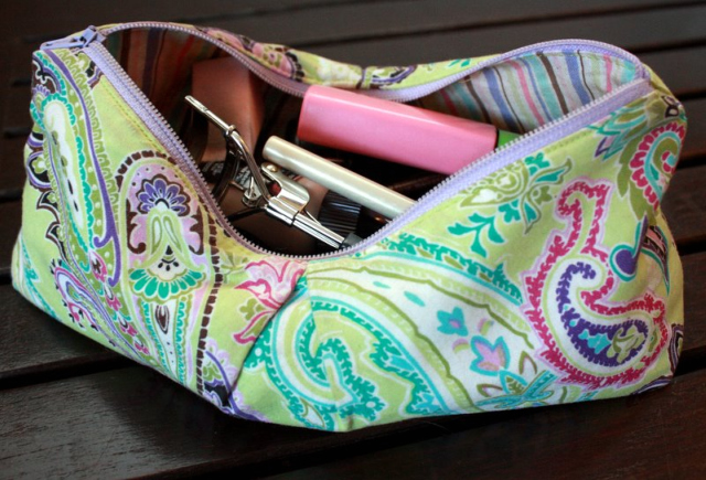 a green paisley makeup bag with assorted makeup inside