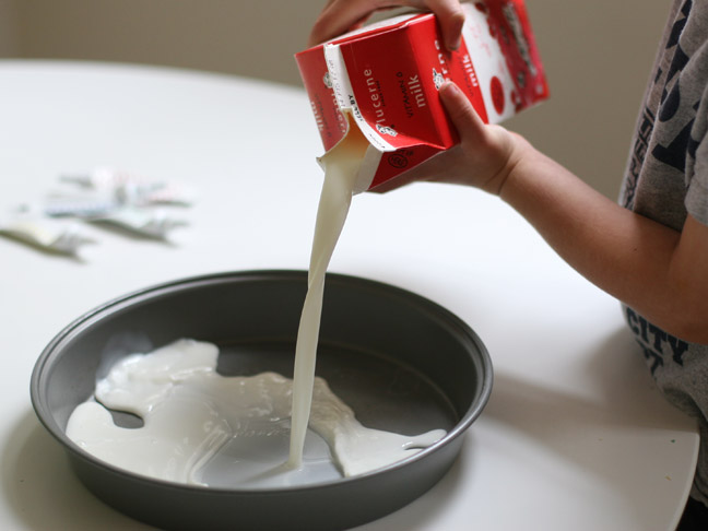 kid pouring milk into pie tin