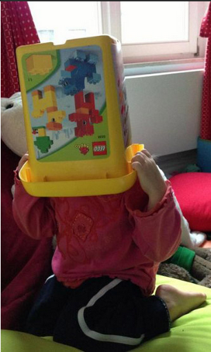 Child pulling lego box over head