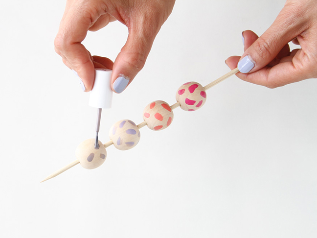 Painting wood beads with nail polish for long DIY necklace.