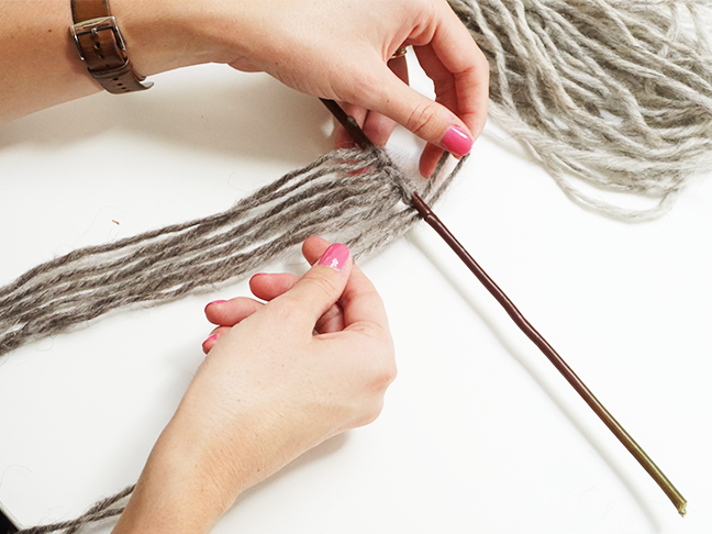 grey yarn folding over the top of the stick