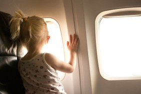 Toddler girl looking out airplane window in flight