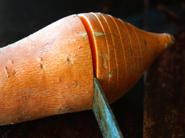 cutting slices into a sweet potato