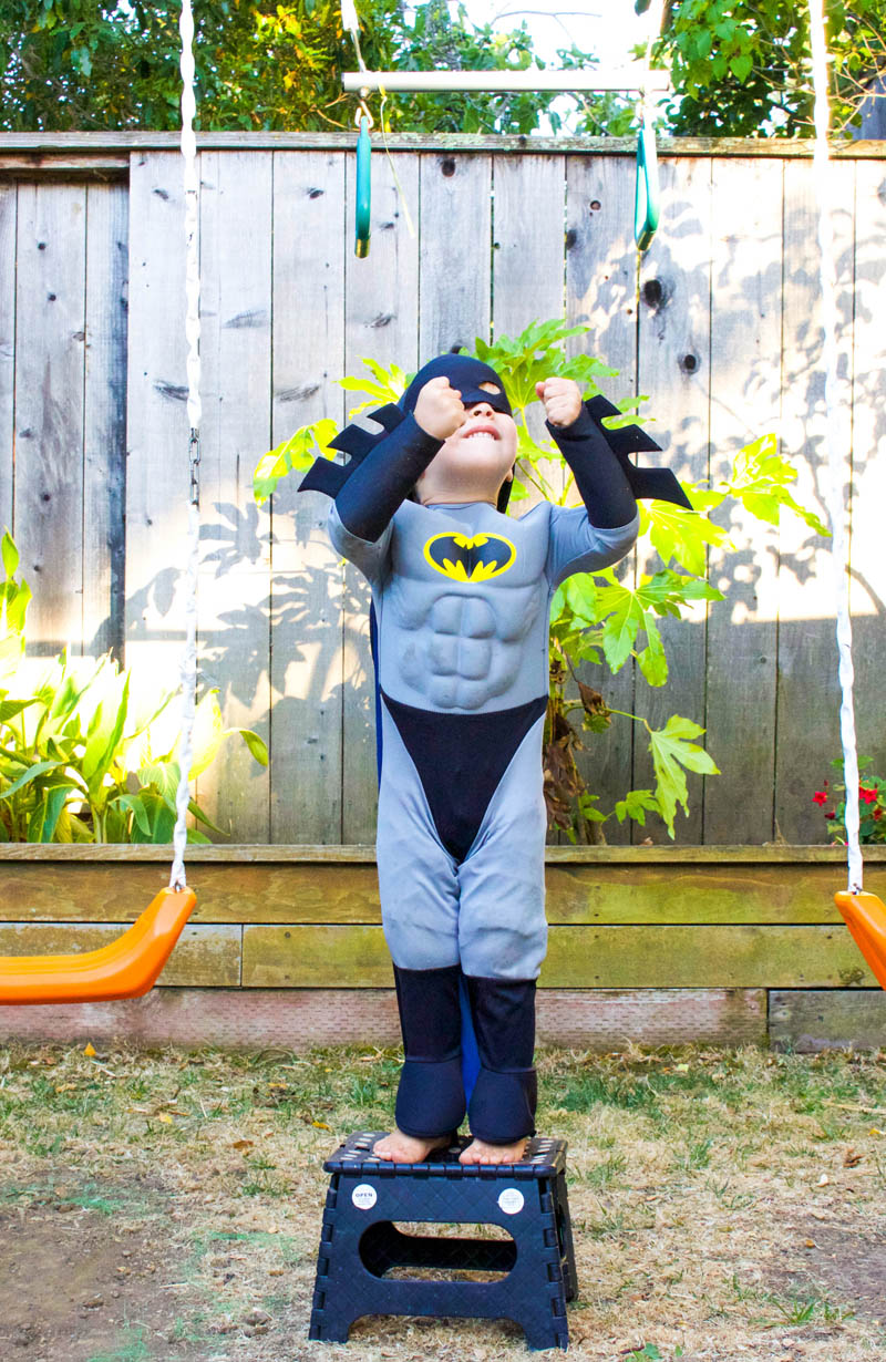 little boy as batman at swing set