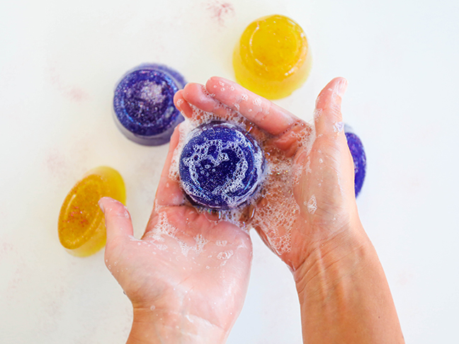 hands holding soapy purple round soap