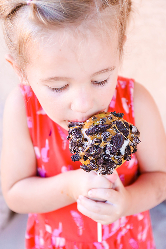 closeup of girl eating caramel apple with oreos