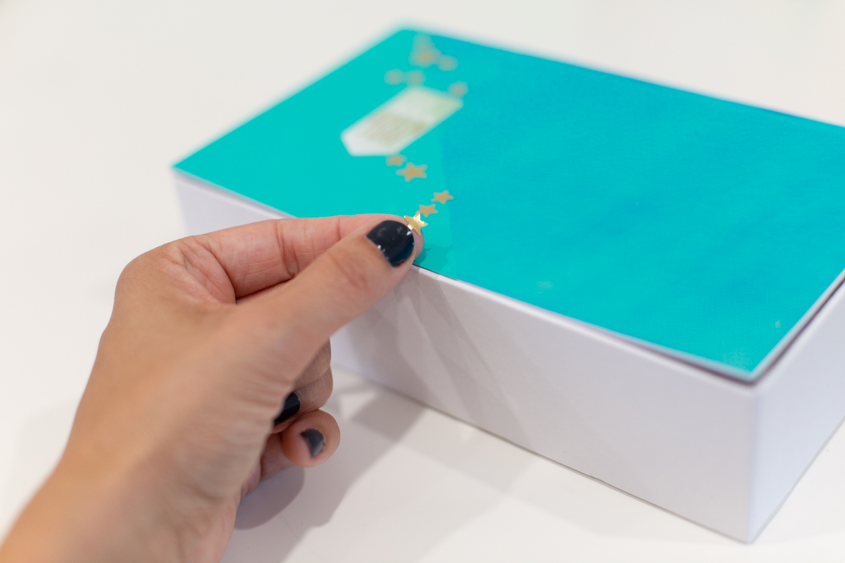 Hand placing stickers on a pencil box