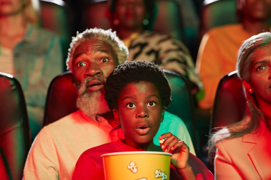 Shocked man watching horror movie with girl in cinema hall