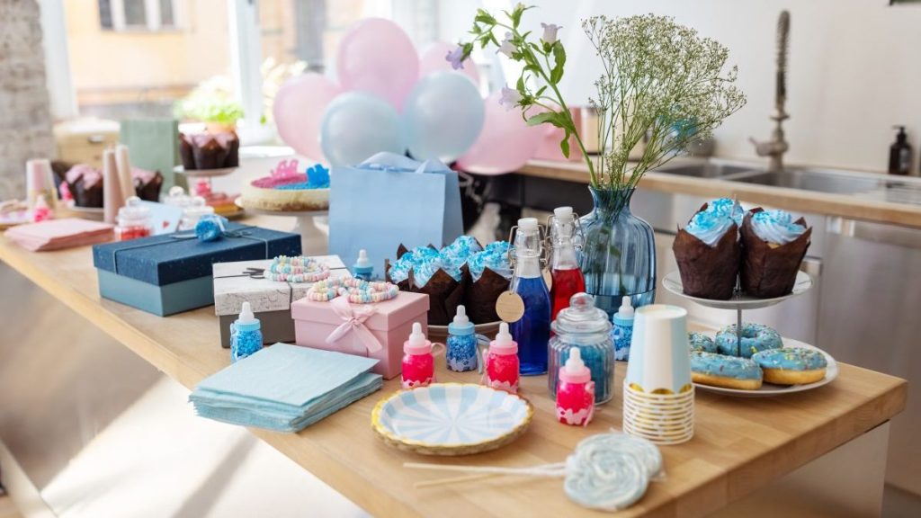 Baby shower party table with sweets. Food and drinks with gifts on decorated table at gender reveal party.
