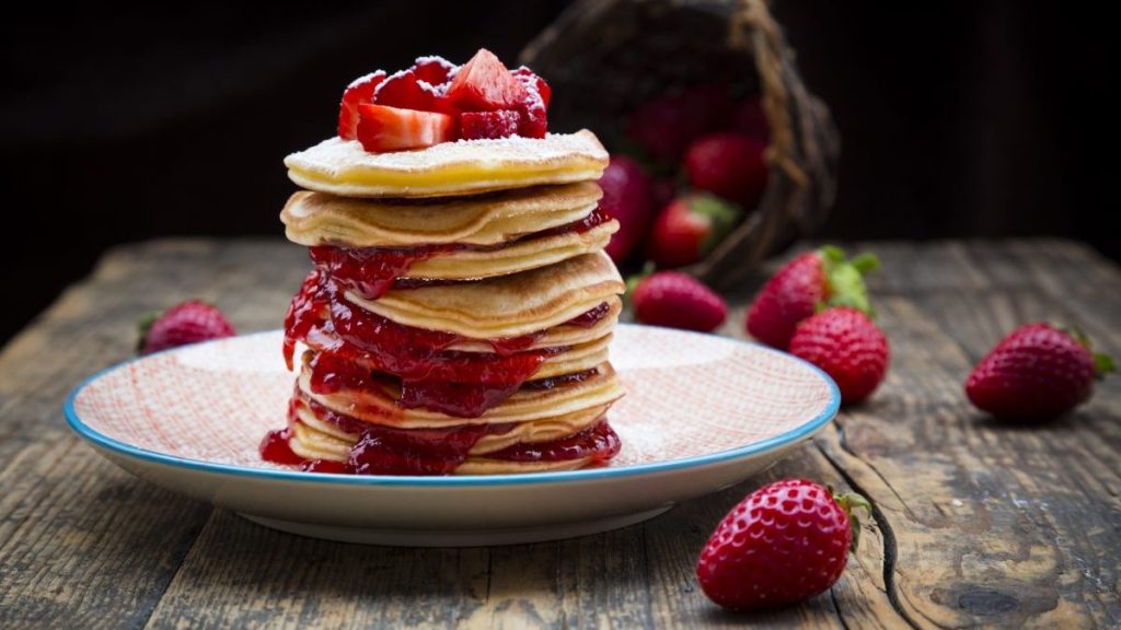 Stack of pancakes with strawberry sauce and strawberries