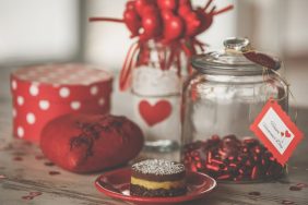 Front view of still life set of romantic red decorations and vegan cake for Valentine's celebration