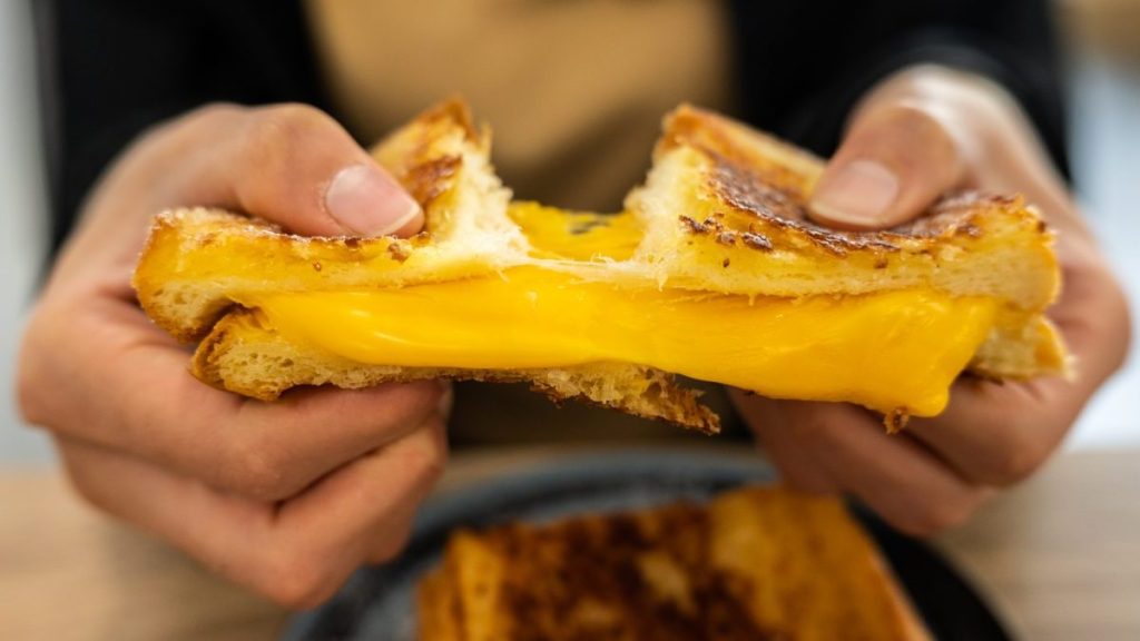 Someone tearing a Cheese Toast before eating.