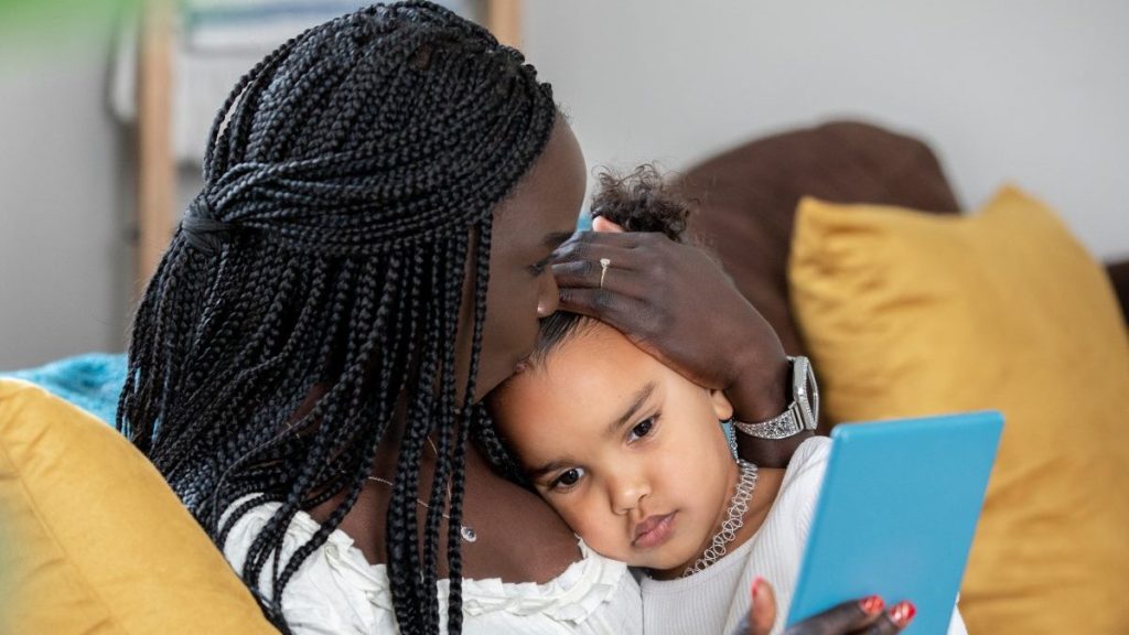 Mother holding child while scrolling through social media