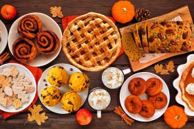 Autumn desserts table scene with a selection of traditional fall sweet treats. Overhead view over a rustic wood background. Pumpkin and apple pies, apple cider donuts, muffins, cookies, tarts.