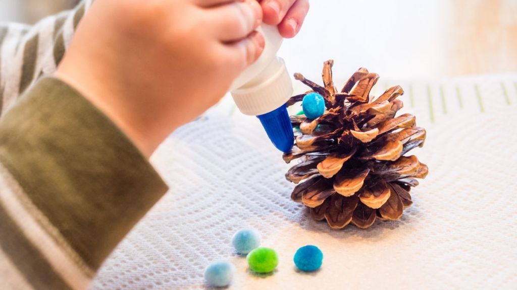 Kid doing DIY craft using pinecone.