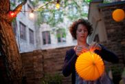 Young woman preparing paper lantern in back yard for garden party